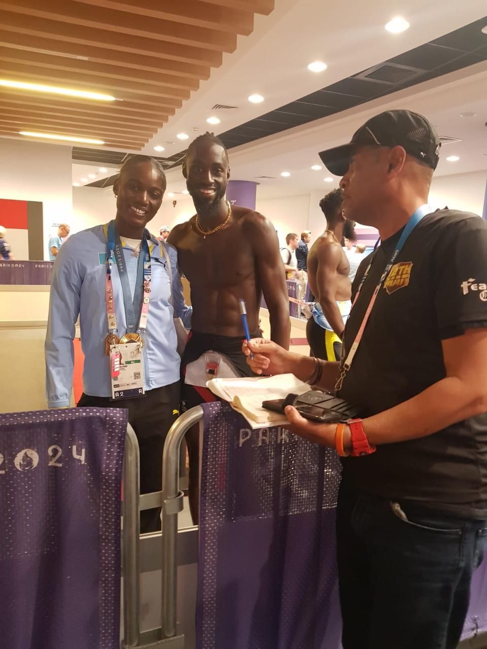 Julien Alfred, left, of Saint Lucia, took time out of the medal ceremony activities to link up with her friend T&T’s Jereem Richards and T&T freelance reporter Andre E. Baptise after the men’s 400-meter first-round heat at the 2024 Summer Olympics yesterday in Saint-Denis, France. On Saturday, Alfred clocked 10.72 seconds to win the women’s 100-meter gold medal. (Image obtained at guardian.co.tt)